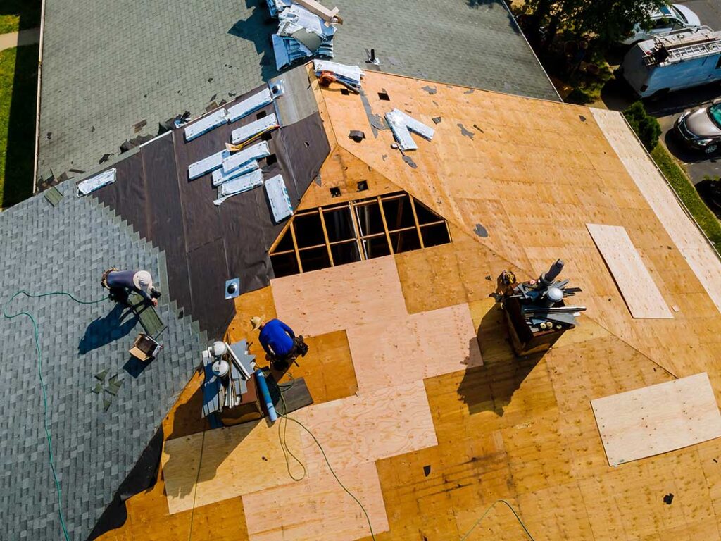 A homeowner examining attic vents and insulation near a roof eave on a sunny day